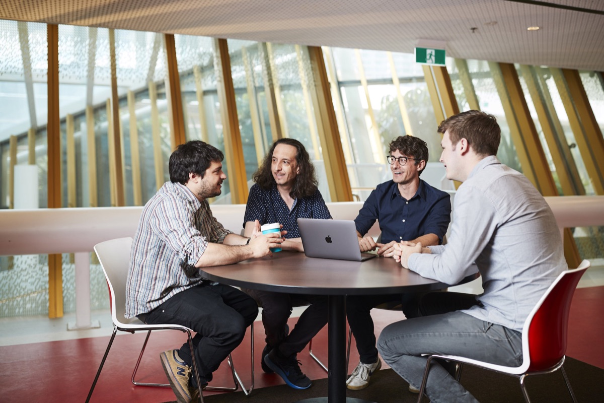 Researchers discussing work around a laptop at RMIT